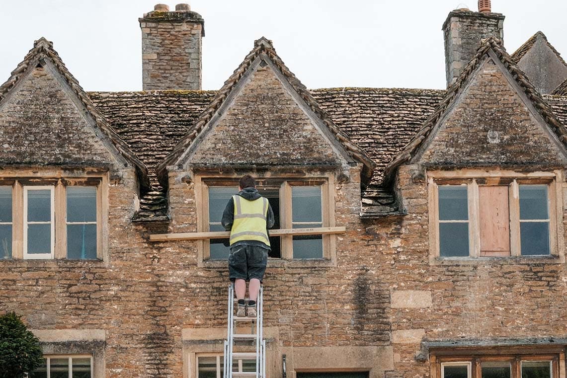 Worker renovating the exterior of a stone property